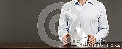 Miniature layout of a house in the hands of a male businessman. On the table. Concept for building or buying safety and protection Stock Photo