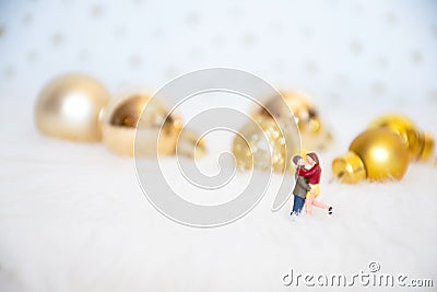 Miniature lover couple with background gold-yellow-gilter christmas ball, merry chistmas and happy new year concept Stock Photo