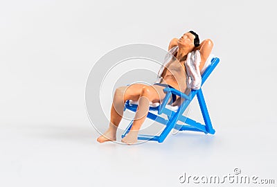 Miniature man relaxing sunbathing on a chair Stock Photo