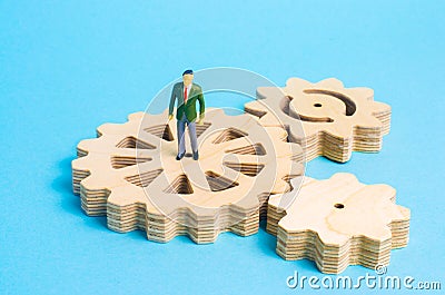 A miniature man is stands on the gears. The concept of the business process, the generation of ideas and plans. Stock Photo