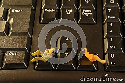 Miniature man and woman sitting on computer keyboard. Family conflict divorce concept Stock Photo