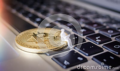 Miniature model of Business man with Laptop sitting on a Bitcoin Stock Photo