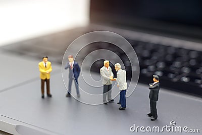 Miniature people: Businessman handshake to business success Online on laptop. Commitment, agreement, investment and partnership c Stock Photo