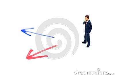 Miniature people: Businessman standing in front of arrow pathway choice. Image use for business decision concept, new the way Stock Photo