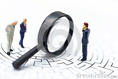Miniature people: Businessman use magnifying glass to find the route on the maze. Concepts of finding a solution, problem solving Stock Photo