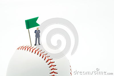 Miniature people businessmen standing with Green Flag Pin on baseball on a white background and red stitching baseball. as backgro Stock Photo