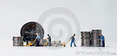 Miniature people carrying coins in a cart and a compass. Stock Photo