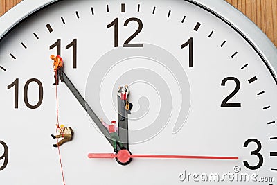 Miniature people climbing a clock Stock Photo