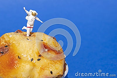 Miniature People concept, close up miniature astronaut standing on muffin, over blue background. Stock Photo