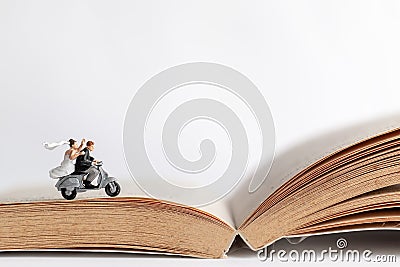 Miniature people : Couple riding the motorcycle on old book Stock Photo