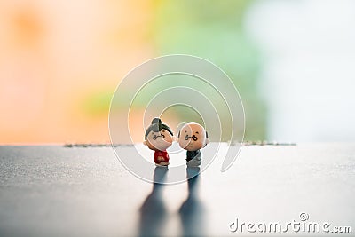 Miniature people, grandfather and grandmother standing on blurry background Stock Photo