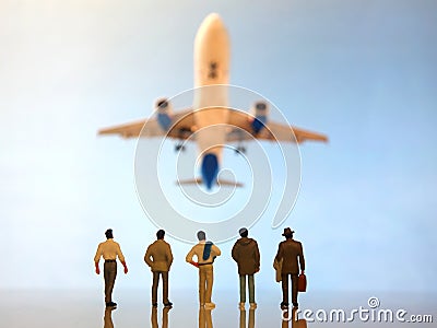 Miniature people. a group of different people watching a flying passenger plane Stock Photo