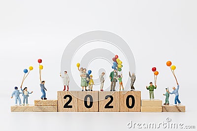 Miniature people : Happy family holding balloon on wooden block number 2020 Stock Photo