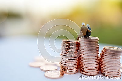 Miniature people: Happy old people sitting on coins stack, Retirement and Life insurance Concept. Stock Photo