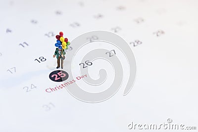 Miniature people holding balloon stand on the calenda, Merry Christmas. Stock Photo