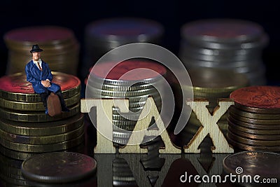 Miniature People. Man sitting on coin stacks with Text. IRPF Taxman Concept. Macro Stock Photo
