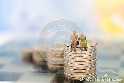 Miniature people, old couple figure standing on top of stack coins . Image use for background retirement planning, Stock Photo