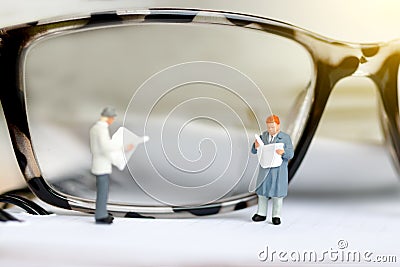 Miniature people reading and standing on book with glasses using as background, Stock Photo