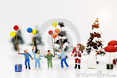 Miniature people: Santa Claus and childrens holding balloon with Christmas Tree. Stock Photo