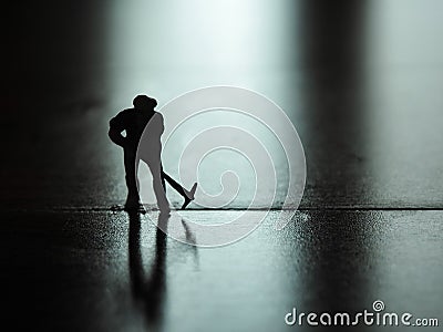 Miniature people silhouette, worker digging on the floor. Stock Photo