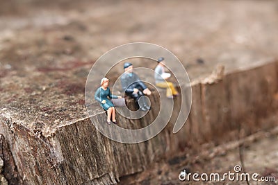 Miniature people sitting down on ledge. Stock Photo