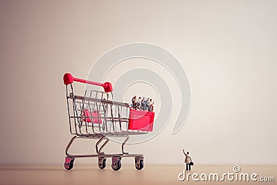 Miniature people sitting on a giant shopping cart. Saving and sh Stock Photo