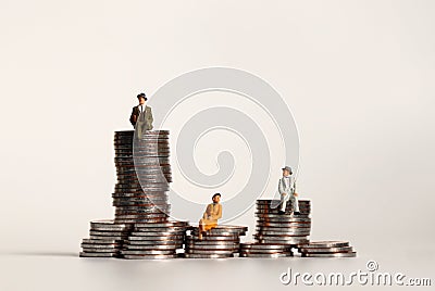 Miniature people sitting on a pile of coins. The concept of income distribution gaps. Stock Photo