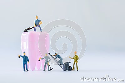 Miniature people, small model human figure clean pink tooth with copy space. Medical and dental concept. Team work on dental care Stock Photo