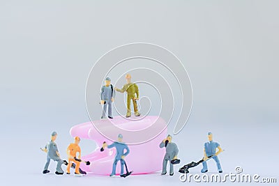 Miniature people, small model human figure clean pink tooth with copy space. Medical and dental concept. Team work on dental care. Stock Photo