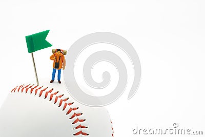 Miniature people standing with Green Flag Pin on baseball on a white background and red stitching baseball. as background travel c Stock Photo