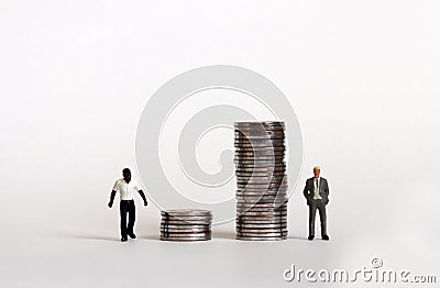 Miniature people standing with a pile of coins. The concept of racial wage discrimination. Stock Photo