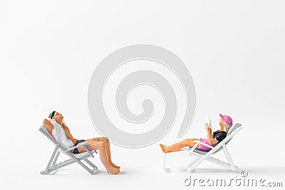 Miniature people sunbathing on deck chairs on white background Stock Photo