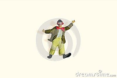 Miniature people toy figure photography. Full body of a clown wearing huge bowties standing on yellow ivory background Stock Photo