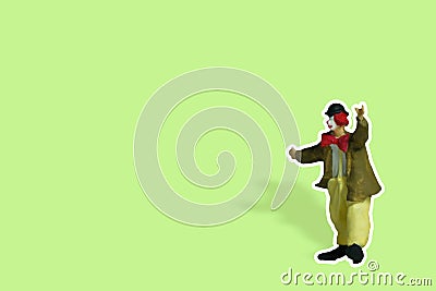 Miniature people toy figure photography. Full body of a clown wearing huge bowties sticker on green background Stock Photo