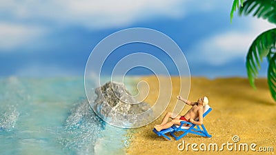 Miniature people toy figure photography. A Men relaxing on beach chair when daylight at seaside Stock Photo