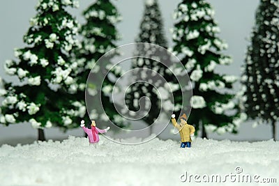 Miniature people toy figure photography. Winter holiday. Kids brother and sister playing snowball throwing in the pine fir forest Stock Photo