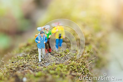 Miniature people : traveler walking on the roads are cluttered with grass. Used to travel to destinations Stock Photo