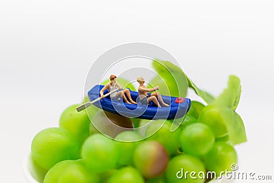 Miniature people : Travelers with paddle boat on the grape. Image use for activities, travel business concept Stock Photo