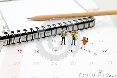 Miniature people, travelers standing on the calendar, mark date for traveling to destination. Used in the travel business concept Stock Photo