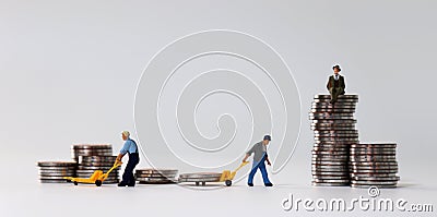 Miniature people at work site with stack coins. Concept of economic inequality. Stock Photo