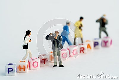 Miniature Photographers taking pictures behind a Group Of Letters forming Word Spelling Stock Photo