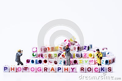 Miniature Photographers taking pictures before a Group Of Letters forming Words Spelling Stock Photo