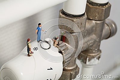 Miniature Plumbers Repairing A Thermostat Stock Photo