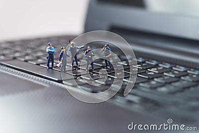 Miniature police squad protecting laptop computer. Technology concept Stock Photo