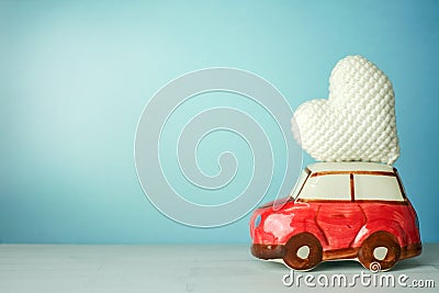 Miniature red car carrying a white heart on cyan background Stock Photo