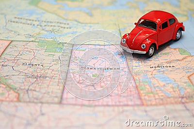 Miniature red car driving on a map of the pairie provinces, canada Stock Photo