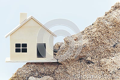 Miniature replica wooden house is located on a sand pile. Stock Photo