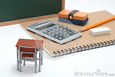 Miniature school desk, chalkboard and calculator on white background. Stock Photo