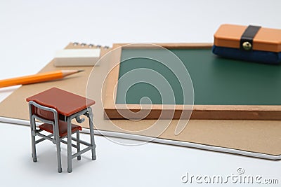 Miniature school desk, chalkboard and notebook on white background. Stock Photo