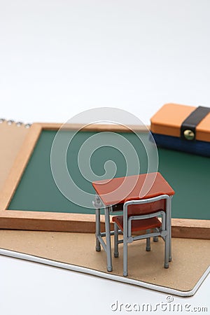 Miniature school desk, chalkboard and notebook on white background. Stock Photo